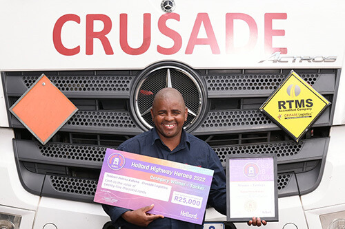 Winning tanker driver, Thabani Kubeka, holding his award, standing in front of a truck