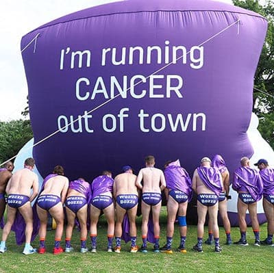 Participants gather at Hollard Daredevil Run 2025 beneath the "I'm running cancer out of town" inflatable