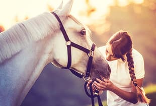 An equestrian covered by Hollard Horse Insurance holding her horse's muzzle