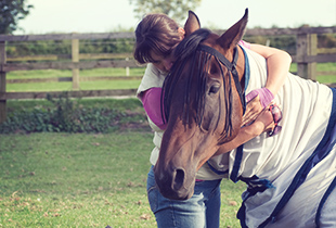 An equestrian covered by Hollard horse insurance hugging her horse