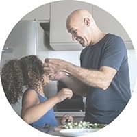 A Hollard Critical Illness benefit client and his daughter cooking dinner in the kitchen.