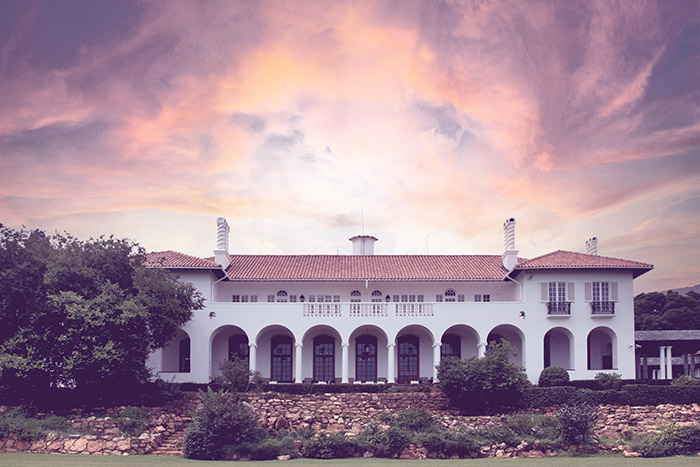 The Facade of Villa Arcadia with the open lawn in the foreground and Johannesburg sunset in the background.
