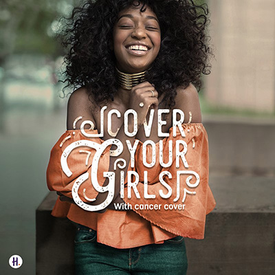 Young African woman standing outdoors laughing with her arms folded. Foreground copy reading "Cover your girls with Cancer Cover".