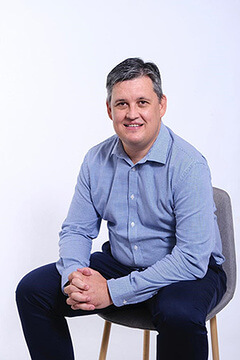 Hollard’s Joint Head of Court Bonds, Chris Troskie, sitting on a chair, smiling.