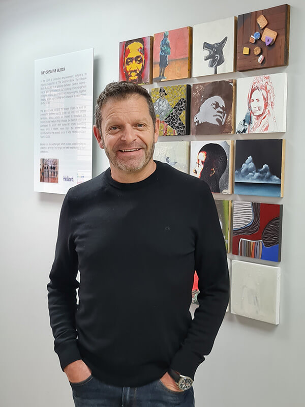 Charl Swarts, Regional General Manager for East and Southern Cape Regions at Hollard standing in front some artwork.