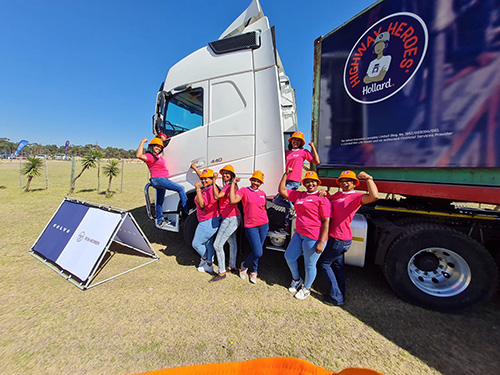 
                        7 WIWIT participants standing on various parts of a large truck flexing their arm-muscles
                    