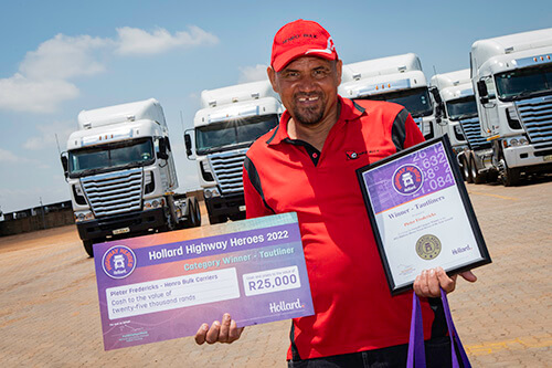 Pieter Fredericks posing with his award outside by trucks